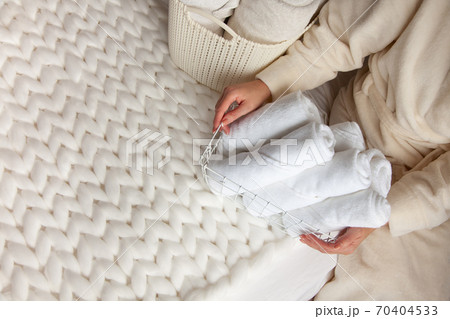 Woman in beige warm robe is folding the clean white hand towels and putting into a metal mesh basket. Topview. 70404533