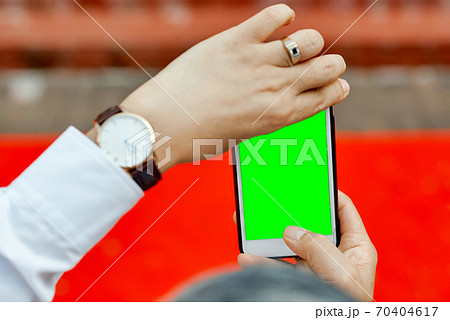 Man's hands shooting with phone empty green screen red carpet  70404617
