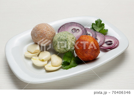 Three balls of snack from lard, with the addition of garlic and red pepper, next to pieces of garlic and onion, sliced into rings Three balls of snack from lard, with the addition of garlic and red pepper, next to pieces of garlic and onion, sliced into rings 70406346