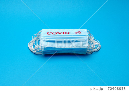 Stack of Disposable blue medical face masks with COVID-19 sign on blue background Stack of Disposable blue medical face masks with COVID-19 sign on blue background 70408053