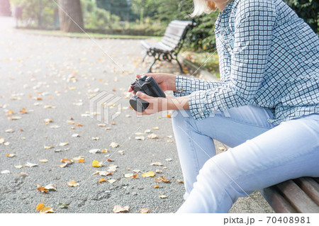 Girl in jeans and a shirt with a film camera in her hands in the park. Preparing for a photo shoot Girl in jeans and a shirt with a film camera in her hands in the park. Preparing for a photo shoot 70408981