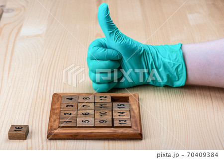 The girl collected the puzzle Game 15 and raised her thumb up. 70409384