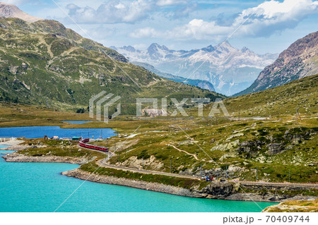 Bernina Express at the White Lake in Ospizio Bernina, Engadin, Switzerland Bernina Express at the White Lake in Ospizio Bernina, Engadin, Switzerland 70409744