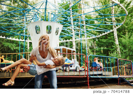 Cheerful little girl her mother have a good time in the park together near attractions Cheerful little girl her mother have a good time in the park together near attractions 70414788