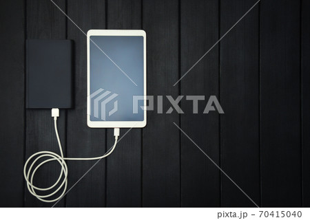 power bank loads tablet PC, smartphone - isolated on wooden background. charging concept. free copyspace. energy 70415040