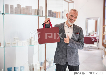 Elegant senior man holding a burgundy bag Elegant senior man holding a burgundy bag 70417332