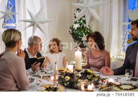 Small girl with parents and grandparents indoors celebrating Christmas. 70418585