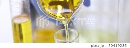 Scientist's hand in rubber glove pours yellow liquid into glass test tube in chemical laboratory closeup Scientist's hand in rubber glove pours yellow liquid into glass test tube in chemical laboratory closeup 70419286
