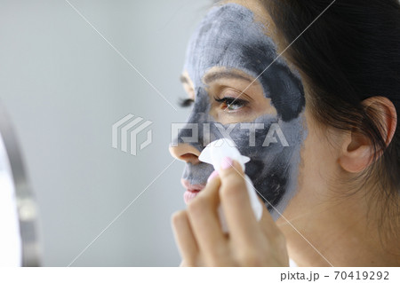 Young woman washes away black clay mask from face portrait Young woman washes away black clay mask from face portrait 70419292