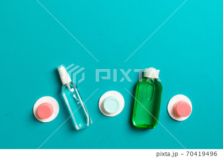 Group of small bottles for travelling on colored background. Copy space for your ideas. Flat lay composition of cosmetic products. Top view of cream containers with cotton pads 70419496