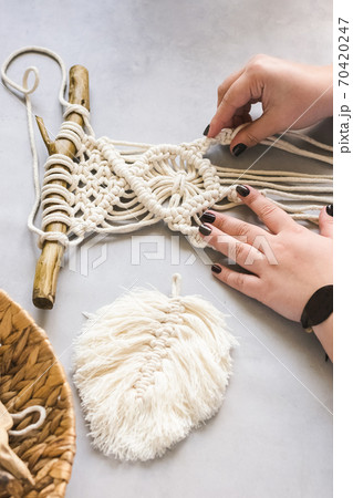 Female hands weave macrame the home workshop. Boho lifestyle. Hobby hobby concept. Selective focus Female hands weave macrame the home workshop. Boho lifestyle. Hobby hobby concept. Selective focus 70420247