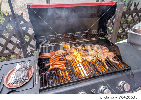 Tomahawk rib beef steak ans sausages on hot black grill with flames bbq 70420635