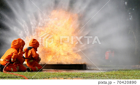 Firefighter fighting with flame using fire hose chemical water foam spray engine Firefighter fighting with flame using fire hose chemical water foam spray engine 70420890