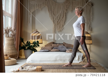 Senior woman working out indoors standing in Tadasana, Mountain Pose 70421118