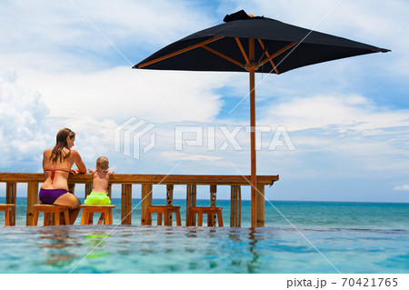 Young mother, happy baby son relaxing at poolside beach bar. 70421765
