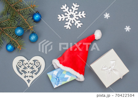 Gift boxes, Santa's hat, fir tree branches with cones on gray background 70422504