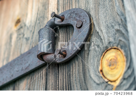 Rusty door hinge with pulled out nails on old wooden doors 70423968