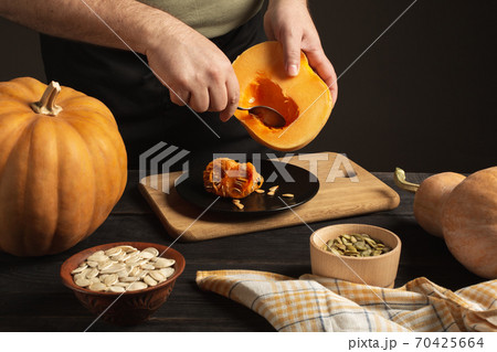 The cook separates the grain from the pumpkin cut in half. The cook separates the grain from the pumpkin cut in half. 70425664