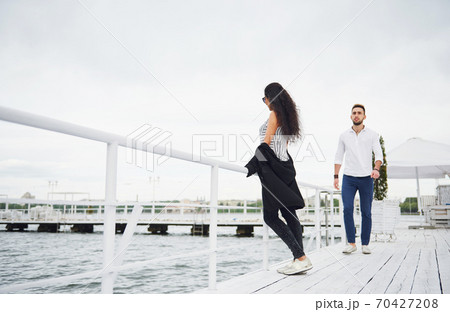 Happy young couple in love in a beautiful dress, posing on the pier near the water Happy young couple in love in a beautiful dress, posing on the pier near the water 70427208