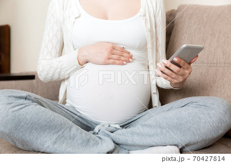 Caucasian pregnant girl using cellphone, resting on bed in home Caucasian pregnant girl using cellphone, resting on bed in home 70427814