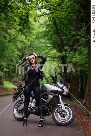 An attractive sexy girl on a sports motorbike posing outside 70428295