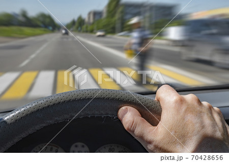 the driver hand on the steering wheel of a car moving at high speed 70428656