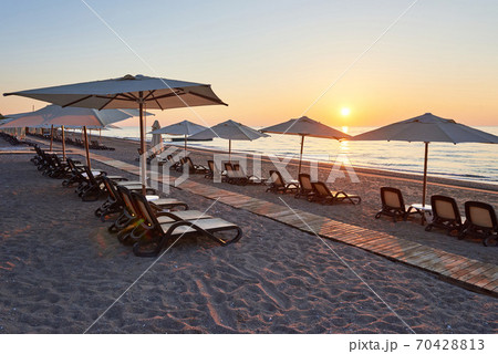 Scenic view of sandy beach on the beach with sun beds and umbrellas open against the sea and mountains. Hotel. Resort. Tekirova-Kemer Scenic view of sandy beach on the beach with sun beds and umbrellas open against the sea and mountains. Hotel. Resort. Tekirova-Kemer 70428813