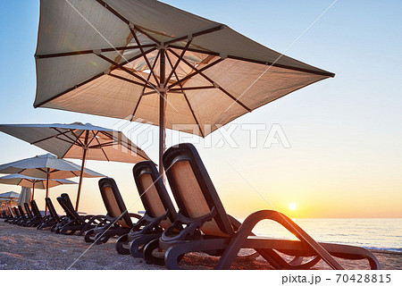 Scenic view of sandy beach on the beach with sun beds and umbrellas open against the sea and mountains. Hotel. Resort. Tekirova-Kemer Scenic view of sandy beach on the beach with sun beds and umbrellas open against the sea and mountains. Hotel. Resort. Tekirova-Kemer 70428815