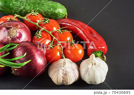 blue onion and garlic, tomato and cucumber on a black background. blue onion and garlic, tomato and cucumber on a black background. 70430695