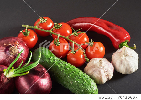 blue onion and garlic, tomato and cucumber on a black background. 70430697