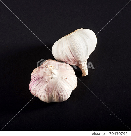 2 fresh garlic bulbs on a black background. 70430792