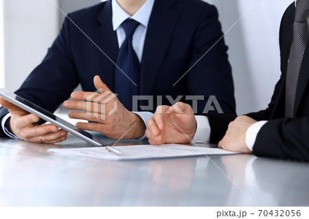 Business people using tablet computer while working together at the desk in modern office. Unknown businessman or male entrepreneur with colleague at workplace. Teamwork and partnership concept Business people using tablet computer while working together at the desk in modern office. Unknown businessman or male entrepreneur with colleague at workplace. Teamwork and partnership concept 70432056