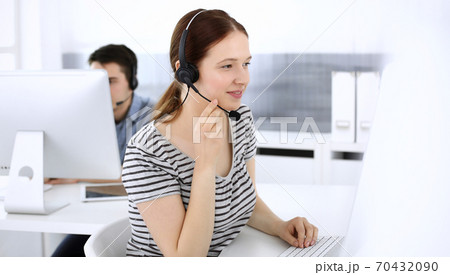 Group of operators at work. Call center. Focus on beautiful woman receptionist in headset at customer service. Business concept and casual striped clothing style 70432090