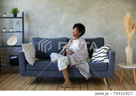 Happy african American young woman sit relax on cozy couch happy to move to new apartment. Smiling black girl rest on comfortable sofa in living room dreaming 70432927