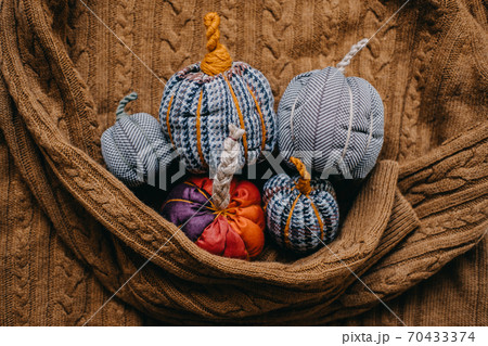 Many Small Fabric Decorative Pumpkin on mustard knitted sweater. Handmade, Autumn Fall Decor, Thanksgiving and Halloween Table Decor. DIY Crafts Many Small Fabric Decorative Pumpkin on mustard knitted sweater. Handmade, Autumn Fall Decor, Thanksgiving and Halloween Table Decor. DIY Crafts 70433374