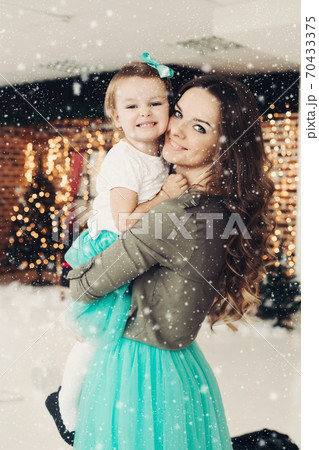 Woman holding cute daughter, posing in studio. Woman holding cute daughter, posing in studio. 70433375