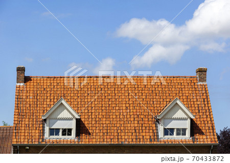 Symmetric red tiled roof with two dormers with rolling shutters 70433872