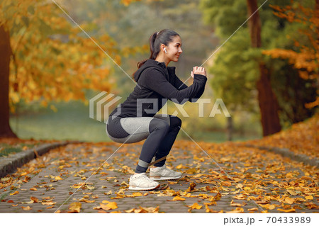 Sports girl in a black top training in a autumn park 70433989