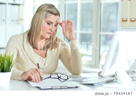 Portrait of senior woman working in office 70434167