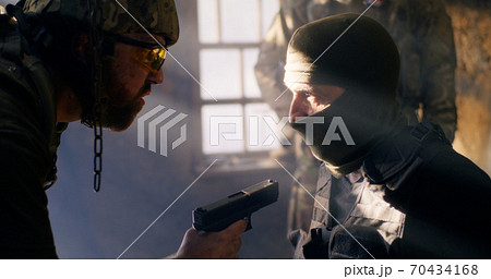 Angry soldier interrogating mature terrorist Angry soldier interrogating mature terrorist 70434168