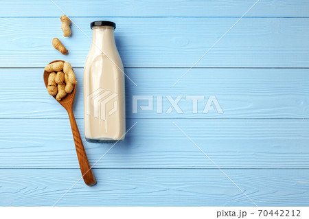 Vegan peanut milk in glass bottle with peanuts on wooden board Vegan peanut milk in glass bottle with peanuts on wooden board 70442212