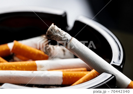 Burning cigarette in a black ash tray Burning cigarette in a black ash tray 70442340