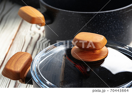 New black cookware with wooden handles close up 70443664