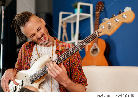 Young man guitar player sitting and performing on a couch Young man guitar player sitting and performing on a couch 70443849