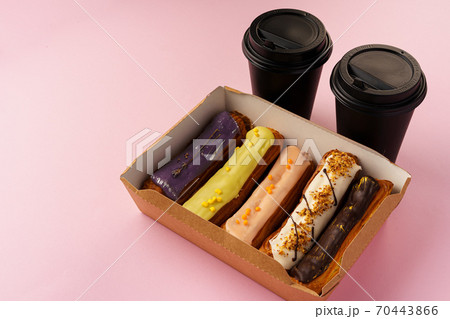 Box of eclairs with takeaway coffee cups on pink background Box of eclairs with takeaway coffee cups on pink background 70443866