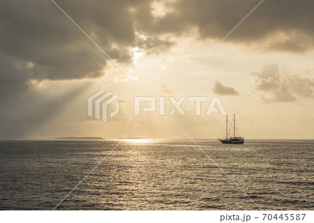 Sunset over the Indian ocean with Maldivian islands on the horizon and silhouette of ship with masts 70445587