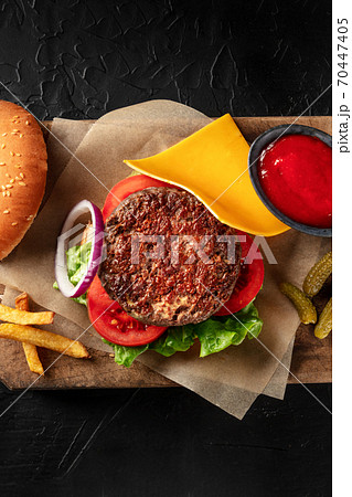 Burger with beef, cheese, onion, tomato, and green salad, with a bun and ketchup, with French fries, overhead shot with a place for text Burger with beef, cheese, onion, tomato, and green salad, with a bun and ketchup, with French fries, overhead shot with a place for text 70447405