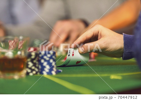 Closeup of gambler's hand holding a pair of aces while playing poker on casino night 70447912