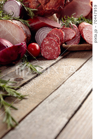 Food tray with delicious salami, ham, fresh sausages, tomato, and rosemary. 70447959