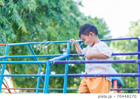 Asian boy hang the metal bar at outdoor playground. 70448270